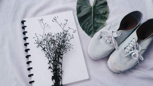 High angle view of book with shoes and plant on fabric