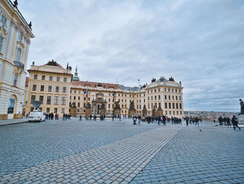 Buildings in town square against cloudy sky