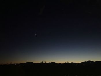 Silhouette landscape against clear sky at night