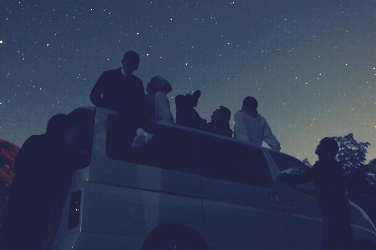 PEOPLE STANDING BY CAR AGAINST SKY