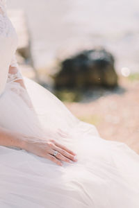 Midsection of bride in wedding dress