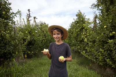 Smiling kid picking apples from the trees