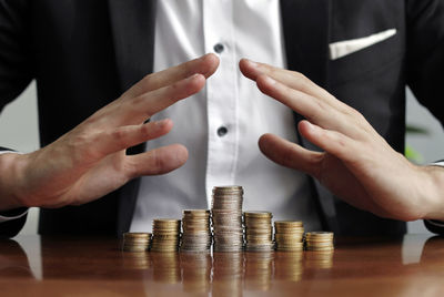 Cropped image of hand holding coin stack on table