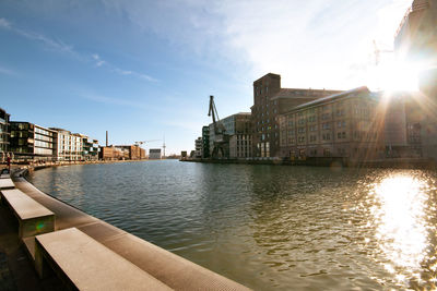 Buildings by river against sky in city