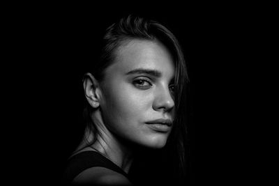 Close-up portrait of young woman over black background