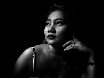 Portrait of young woman against black background