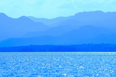 Scenic view of sea and mountains against blue sky