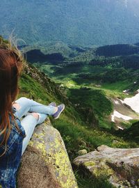 High angle view of woman sitting on rocky mountains
