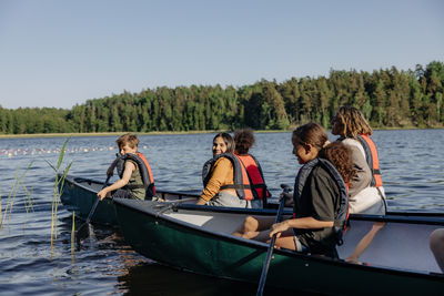 Kids doing kayaking with counselor on lake during sunny day at summer camp