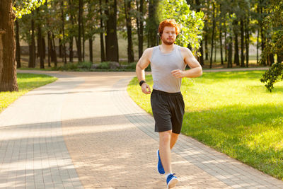 Full length portrait of man running on footpath
