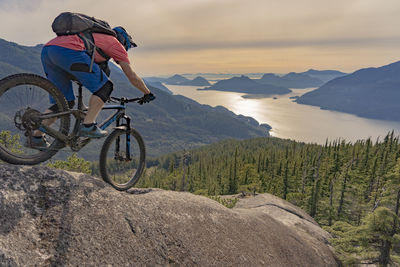 Side view of man riding bicycle on mountain