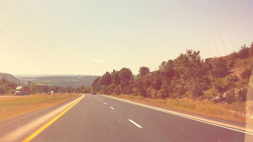 Road by trees against clear sky