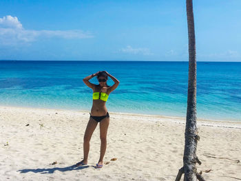 Full length of woman on beach by sea against sky