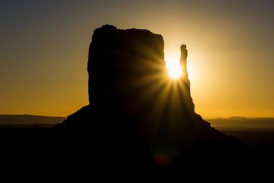 Scenic view of silhouette rock formation against sky during sunset