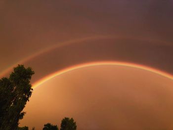 Low angle view of rainbow against sky at sunset