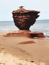Rock on beach against sky