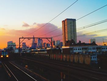 High angle view of railroad tracks by buildings in city at sunset