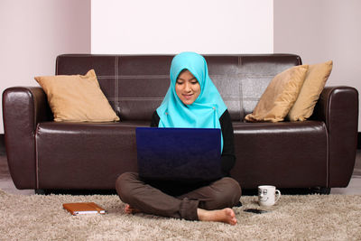 Young woman in hijab using laptop at home