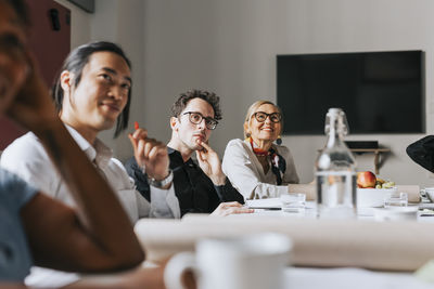 Male and female business people attending meeting in board room at office