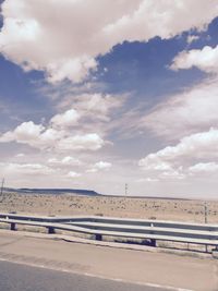 Road by sea against cloudy sky