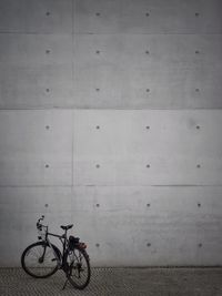 Bicycle parked against wall on street