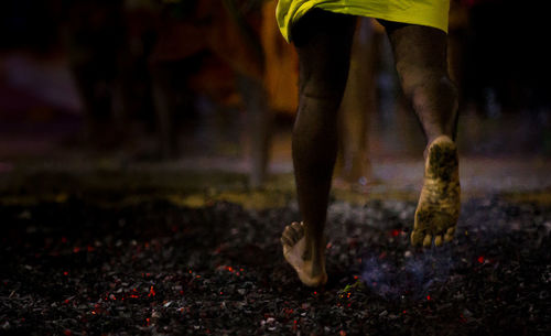 Low section of man running barefoot on hot coals