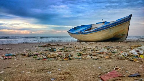 Boat moored on beach against sky