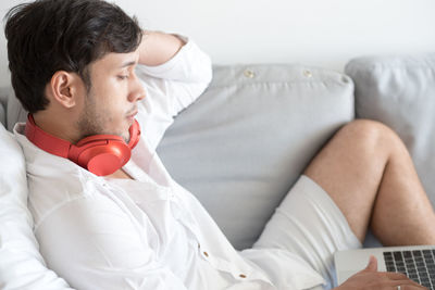 Man listening music while using digital tablet on sofa at home