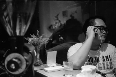 Portrait of man using mobile phone while sitting on table