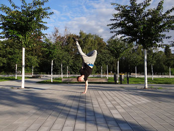 Young man doing handstand on walkway at park