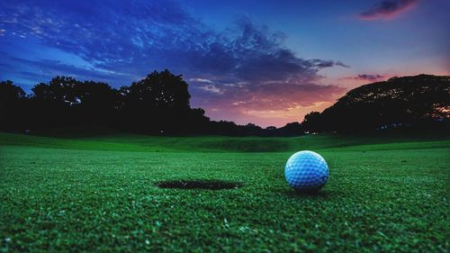 Ball on golf course against sky during sunset