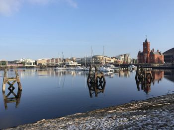 Sailboats moored at harbor against buildings in city