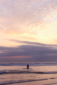 Silhouette man on beach against sky during sunset