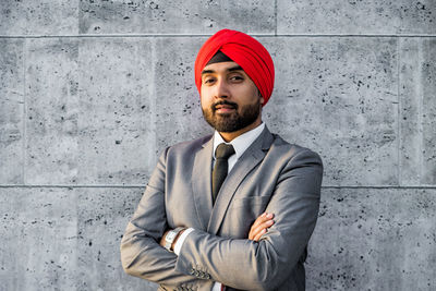 Portrait of smiling businessman wearing turban against wall