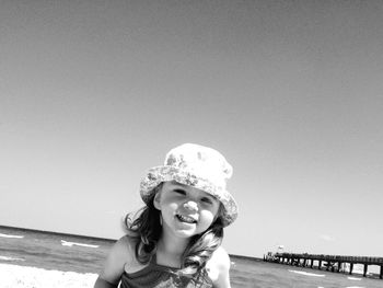 Portrait of smiling girl enjoying at beach against clear sky