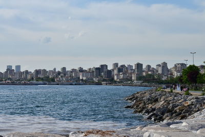 Sea by buildings against sky in city