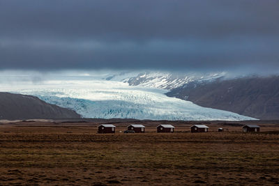 5 cabins with a scenic view of an icelandic glacier in the background with low clouds