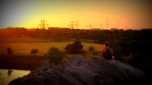 Man on landscape against sky at sunset