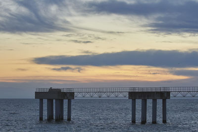 Pier on sea against sky during sunset