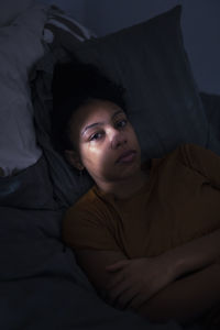 Portrait of crying young woman lying in bed