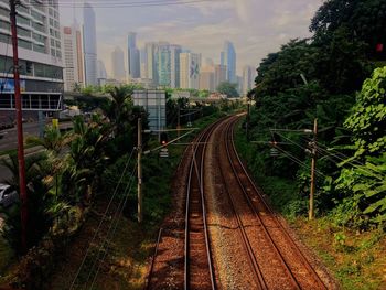 Railroad tracks in city against sky