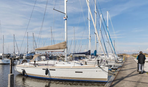 Sailboats moored at harbor against sky