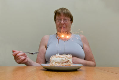 Midsection of young woman drinking glass on table