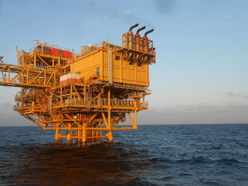 Traditional windmill by sea against sky