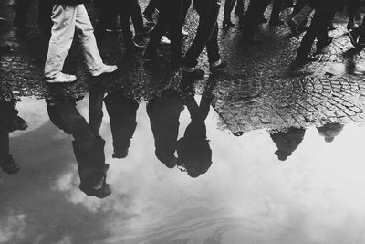 Reflection of people walking on footpath in puddle