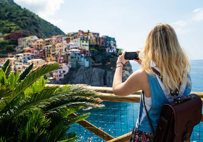 Woman photographing with cityscape against sky