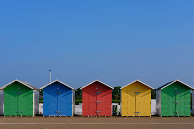 Multi-coloured beach huts in eastbourne beneath a clear blue sky in the summer