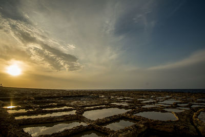 Salt flats against sky at sunset