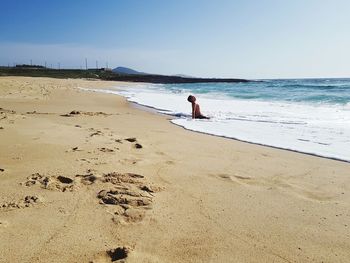 Rear view of man on beach against sky