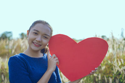 Portrait of a smiling young woman holding heart